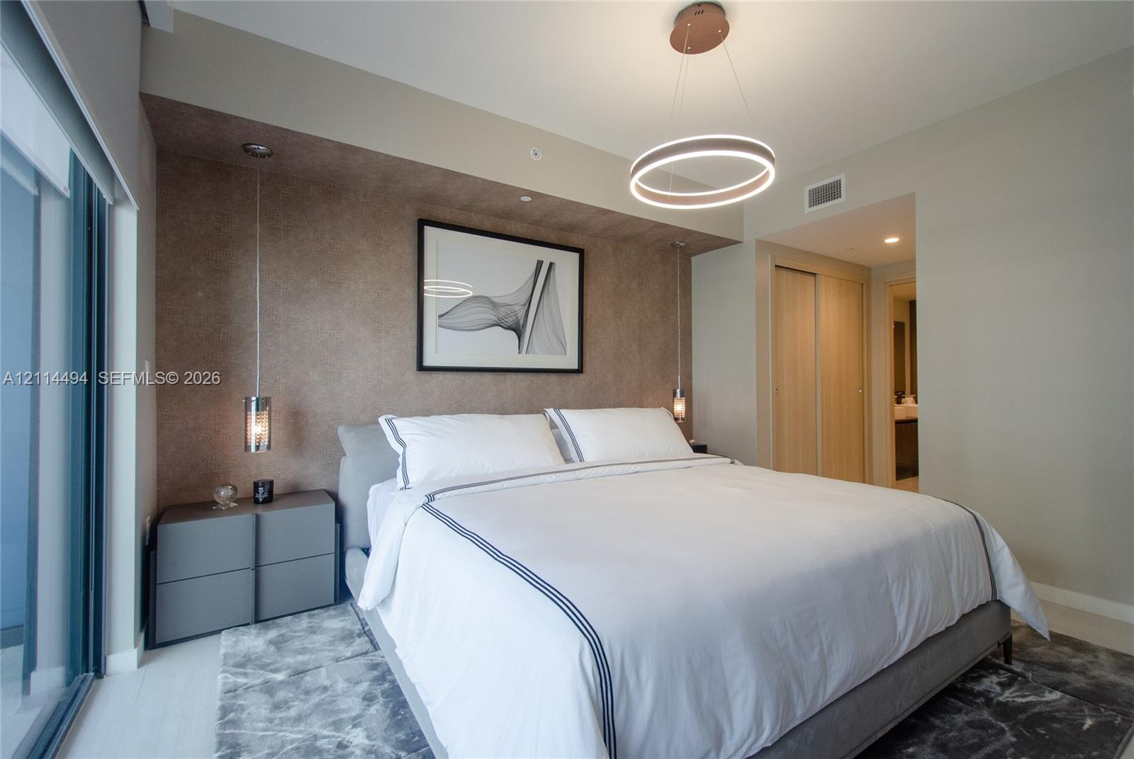 Textured accent wall with a recessed alcove, contemporary circular LED pendant light, and dual cylindrical glass-shade hanging pendants
