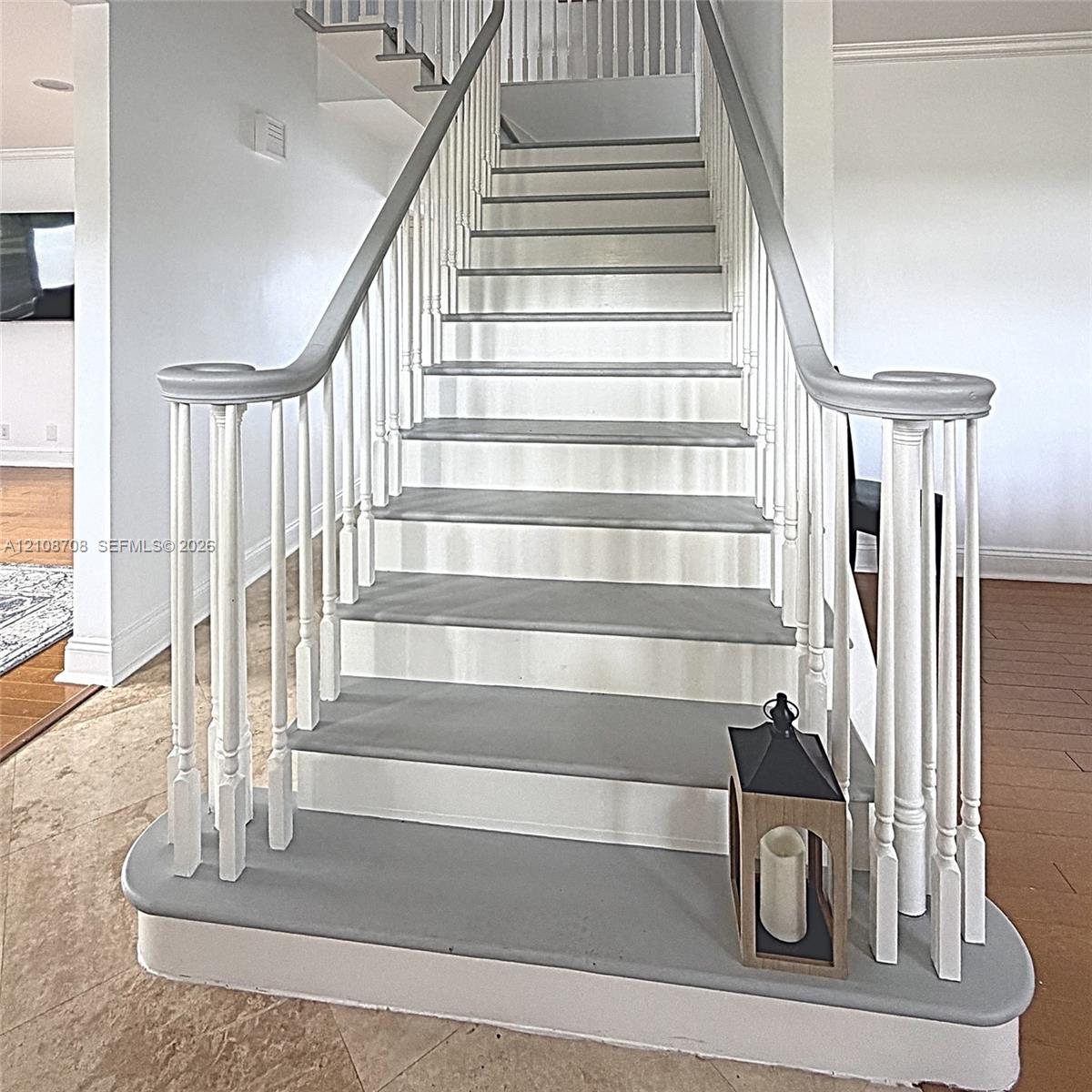Staircase featuring white balusters, painted treads, and a curved handrail