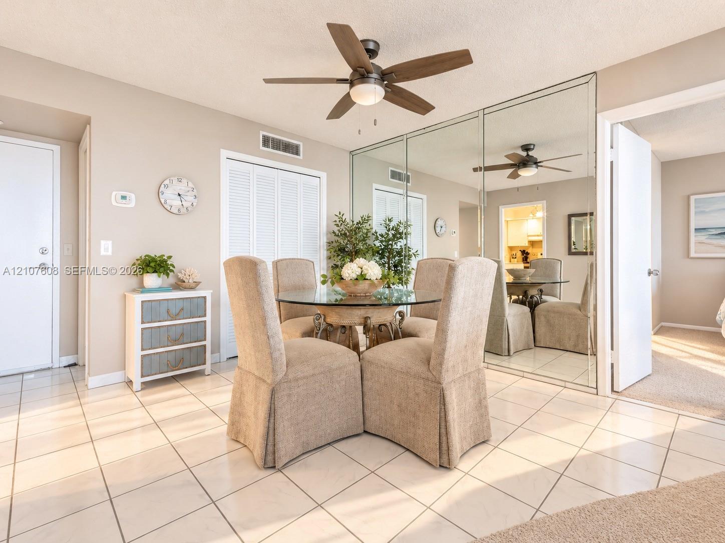 Ceramic tile flooring, full-wall mirrored closet doors, and a ceiling fan with integrated lighting