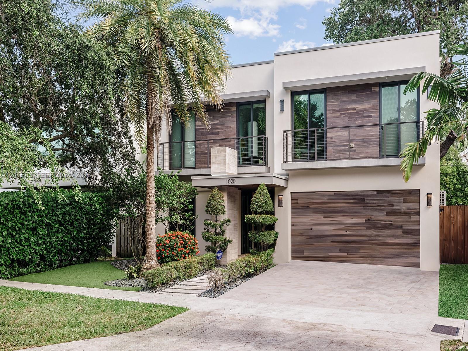 Modern two-story exterior featuring smooth stucco siding, horizontal wood-finish cladding, second-level balconies with metal railings, and an attached