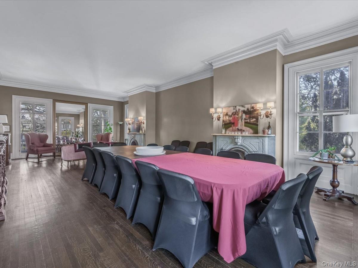 Dining area with ornamental molding, dark wood-style floors, and a fireplace