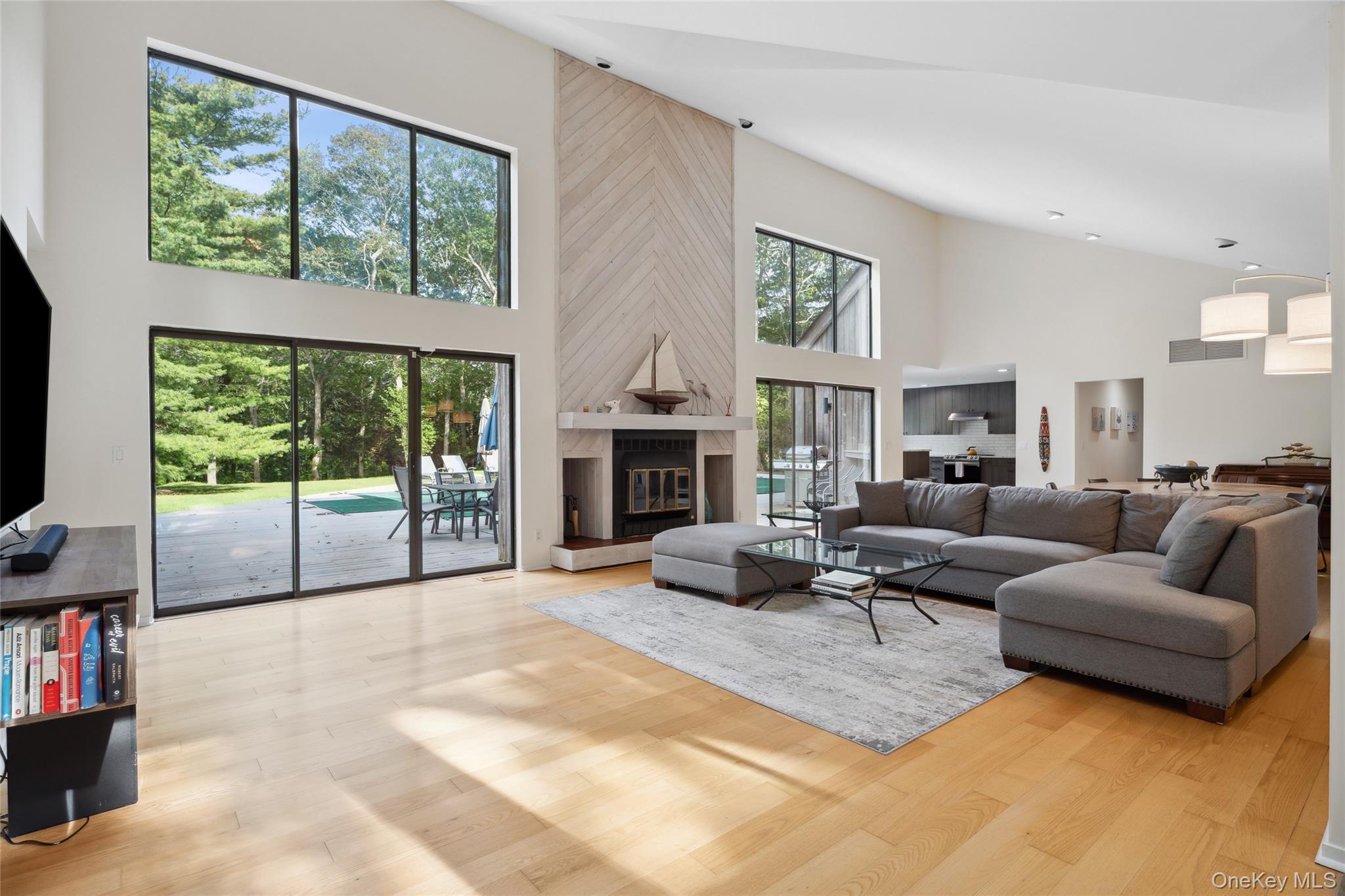 Living room with a towering ceiling, light wood-style floors, and a large fireplace