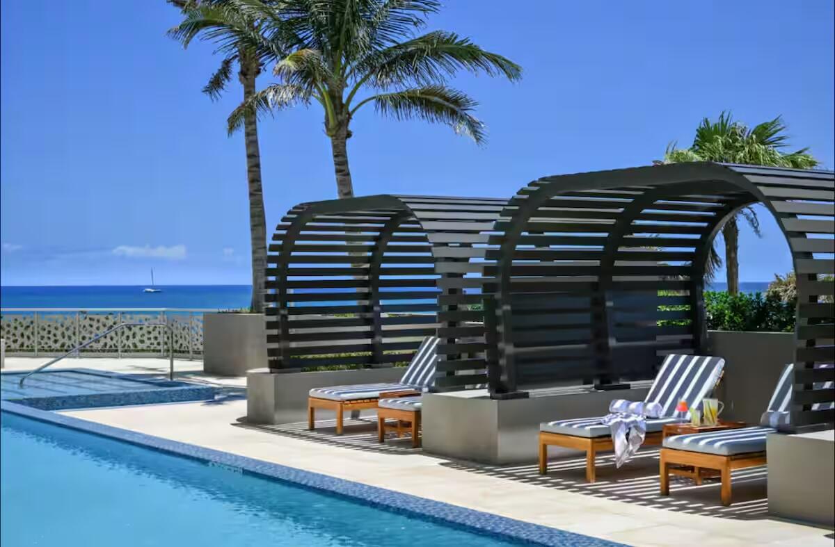Swimming pool with integrated spa, adjacent to a patio featuring two covered lounge structures